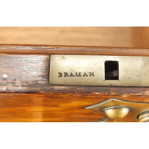 110 - Victorian oak three bottle tantalus with Bramah lock, brass mounts, fitted interior and base drawer ... 