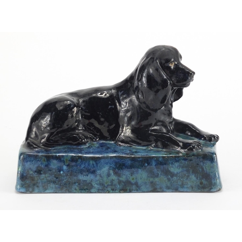 944 - Stella Crofts pottery model of a recumbent spaniel, with a black and mottled blue glaze, incised Ste... 