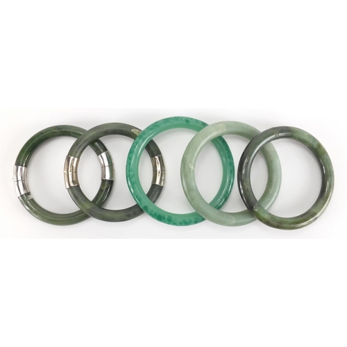 699 - Five Chinese green jade bangles, two with white metal mounts, the largest 8.5cm in diameter, approxi... 