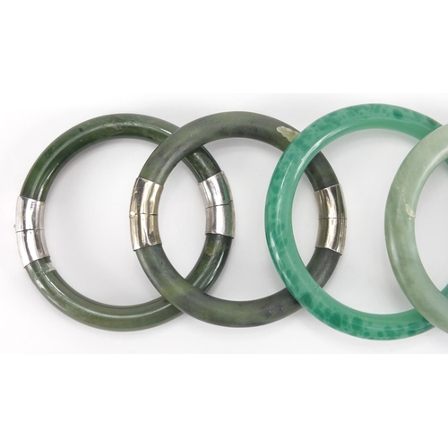 699 - Five Chinese green jade bangles, two with white metal mounts, the largest 8.5cm in diameter, approxi... 