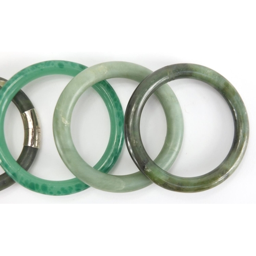 699 - Five Chinese green jade bangles, two with white metal mounts, the largest 8.5cm in diameter, approxi... 