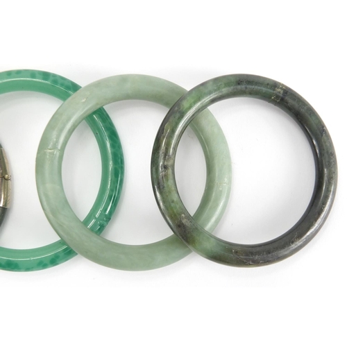 699 - Five Chinese green jade bangles, two with white metal mounts, the largest 8.5cm in diameter, approxi... 