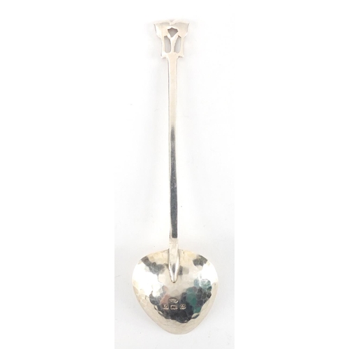 1040 - Arts & Crafts hammered silver spoon with fig shaped bowl and stylised floral finial, by A E Jones, B... 