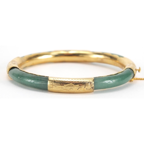 700 - Chinese green jade bangle with gold coloured metal mounts, 7.8cm in diameter, approximate weight 24.... 