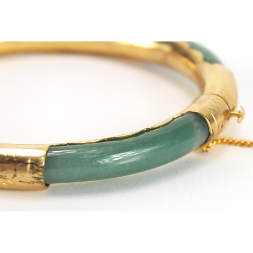 700 - Chinese green jade bangle with gold coloured metal mounts, 7.8cm in diameter, approximate weight 24.... 