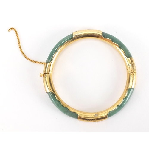 700 - Chinese green jade bangle with gold coloured metal mounts, 7.8cm in diameter, approximate weight 24.... 