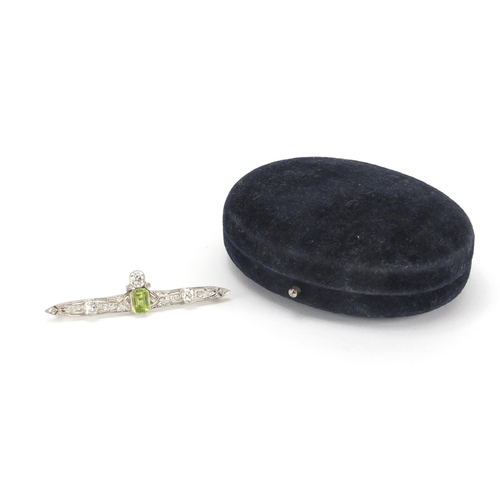 1043 - Art Deco unmarked white metal diamond and green stone bar brooch, housed in a Kendal & Dent velvet l... 