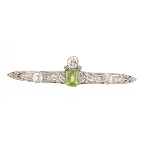 1043 - Art Deco unmarked white metal diamond and green stone bar brooch, housed in a Kendal & Dent velvet l... 