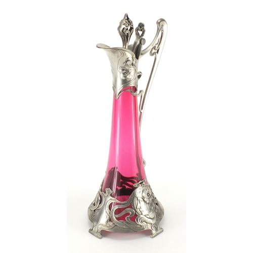 1021 - Art Nouveau pewter and cranberry glass lined ewer in the style of WMF, the pewter body cast with a s... 