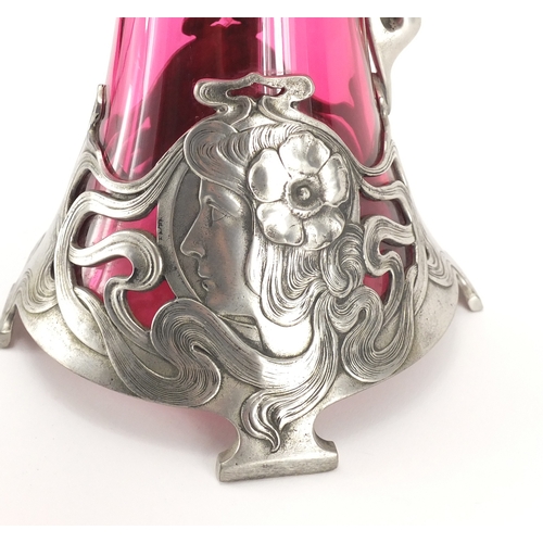 1021 - Art Nouveau pewter and cranberry glass lined ewer in the style of WMF, the pewter body cast with a s... 