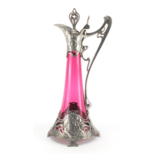 1021 - Art Nouveau pewter and cranberry glass lined ewer in the style of WMF, the pewter body cast with a s... 