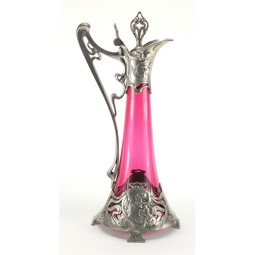 1021 - Art Nouveau pewter and cranberry glass lined ewer in the style of WMF, the pewter body cast with a s... 