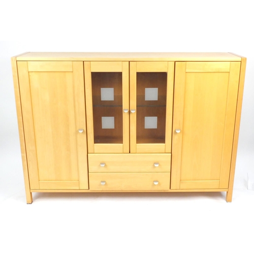 4 - Modern light wood side unit, fitted with a pair of central glazed doors above two drawers, flanked b... 
