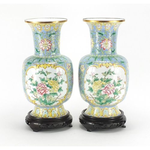2173 - Pair of Chinese Canton enamel vases, hand painted with flowers raised on carved hardwood stands, eac... 