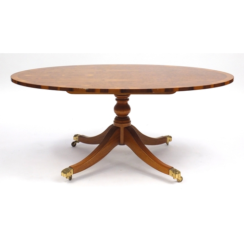 102 - Yew oval coffee table, with  brass paw feet, 51cm H x 121cm W x 69cm D