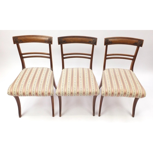 7 - Set of six Regency mahogany dining chairs, with carved top rails and striped upholstered stuff over ... 