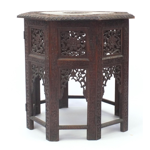 33 - Indian hardwood octagonal folding table profusely carved and pierced with flowers, 56.5cm high x 55c... 