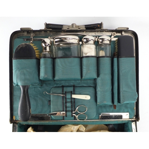 2224 - Vintage black leather vanity case, housing glass bottles with silver plated lids and ebonised handle... 