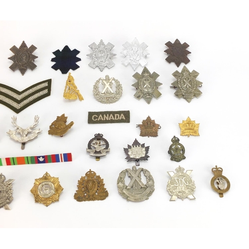 217 - Military interest cap badges and cloth patches including The Cameron Highlanders, British American a... 