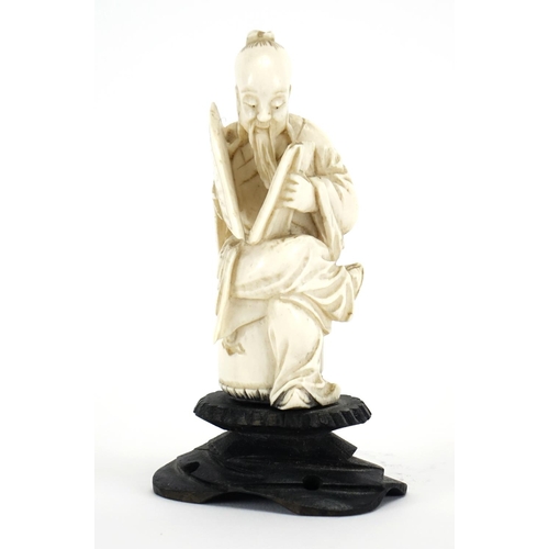 412 - Chinese ivory carving of a seated man holding a fan with calligraphy, raised on a carved hardwood st... 