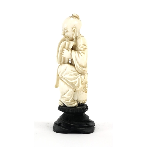 412 - Chinese ivory carving of a seated man holding a fan with calligraphy, raised on a carved hardwood st... 