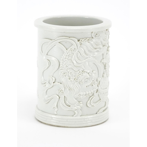 339 - Chinese Blanc de Chine porcelain brush pot, finely decorated in relief with Qilin lions amongst clou... 