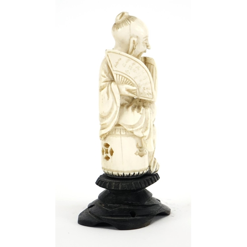 412 - Chinese ivory carving of a seated man holding a fan with calligraphy, raised on a carved hardwood st... 