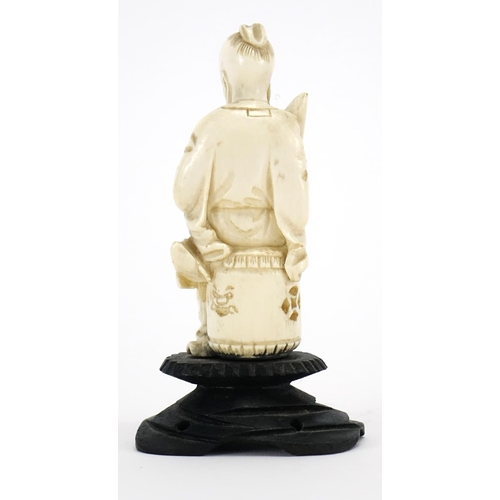 412 - Chinese ivory carving of a seated man holding a fan with calligraphy, raised on a carved hardwood st... 