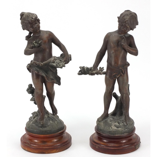 476 - Pair of Spelter figures of a young boy and girl, each raised on a turned wooden base, 34cm high