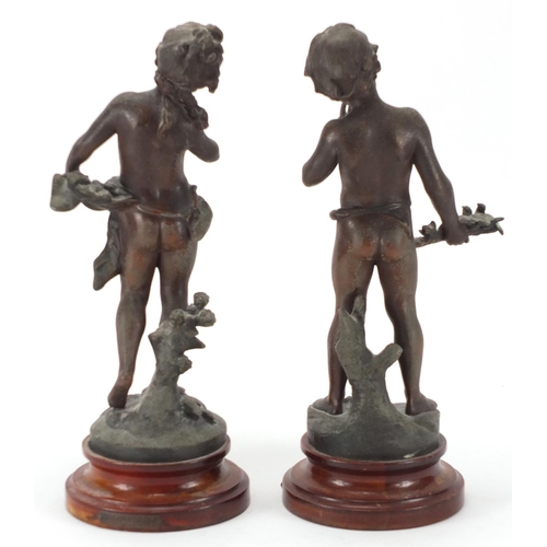 476 - Pair of Spelter figures of a young boy and girl, each raised on a turned wooden base, 34cm high