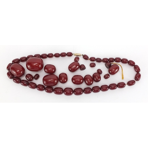 810 - Cherry amber coloured bead necklace and loose graduated beads, approximate weight 93.0g