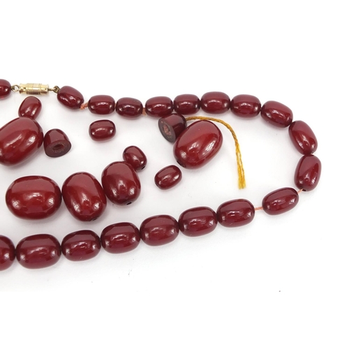 810 - Cherry amber coloured bead necklace and loose graduated beads, approximate weight 93.0g