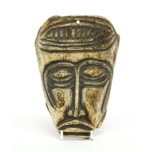 468 - Antique tribal interest bone apron carved in the form of a head, possibly Napalese, 18cm x 13cm