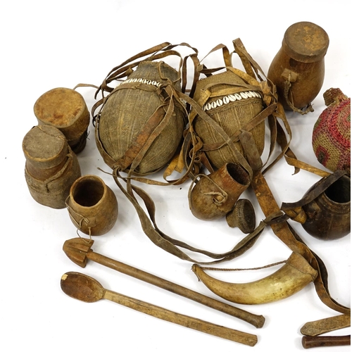 473 - Tribal woodenware including spoons, drums and water carriers with cowry shells, the largest 52cm in ... 