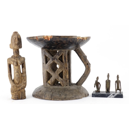 472 - Tribal art comprising a Dogon carved wood figure, three bronze figures raised on a rectangular black... 