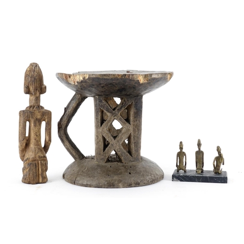 472 - Tribal art comprising a Dogon carved wood figure, three bronze figures raised on a rectangular black... 