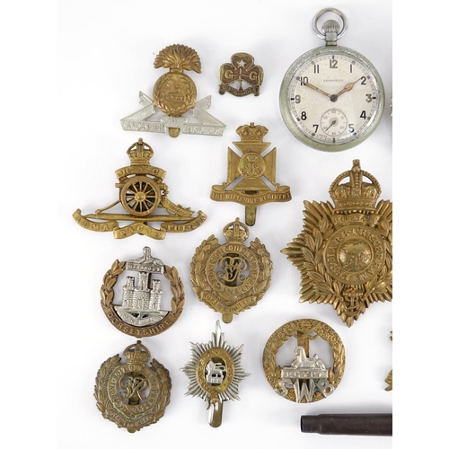 215 - Group of British Military cap badges and a Military issue Leonidas pocket watch