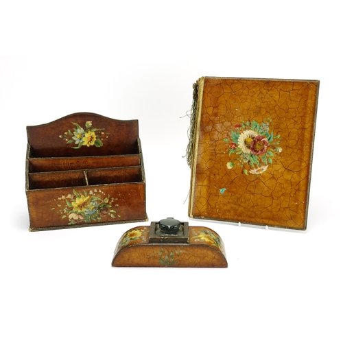 23 - Three piece leather desk set comprising a letter rack, inkwell and blotter, each hand painted with f... 