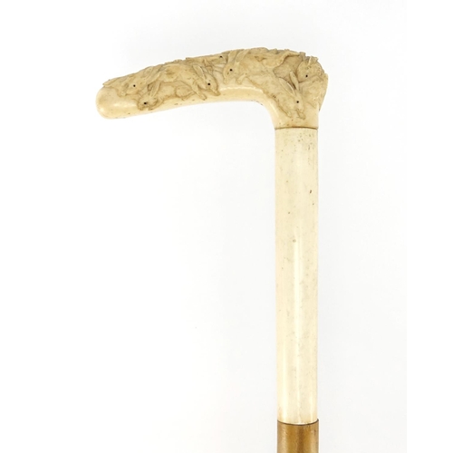 79 - Oriental hyde walking stick with ivory handle, finely carved with rabbits, 87cm in length