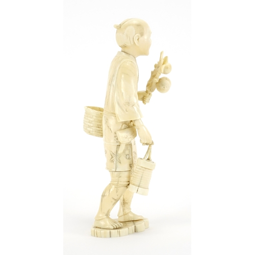 411 - Japanese carved ivory okimono of a man carrying fruit, character marks to the base, 23cm high