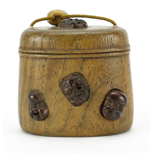 368 - Japanese oval wooden inro with carved ivory Ojime, the inro having applied Noh masks, 8cm high