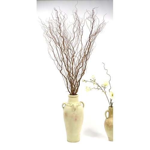 64 - Two floor standing terracotta vases, with artificial flowers, the largest vase 78cm high