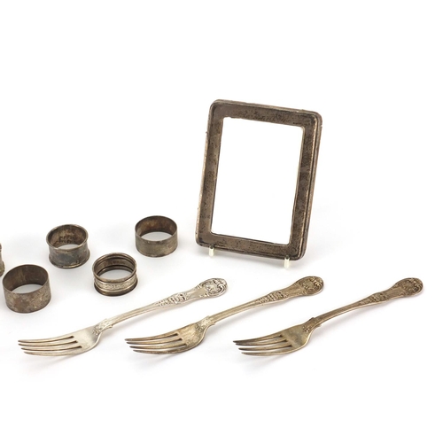 2390 - Silver items comprising three Georgian table forks, eight napkin rings and rectangular photo frame, ... 