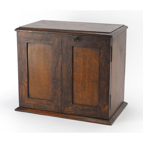 2101 - Oak smokers cabinet opening to reveal two drawers and a revolving pipe rack, 30cm H x 34.4cm W x 21c... 