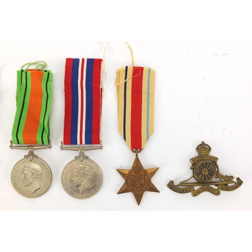 618 - Four British Military World War II medals and a Royal artillery cap badge