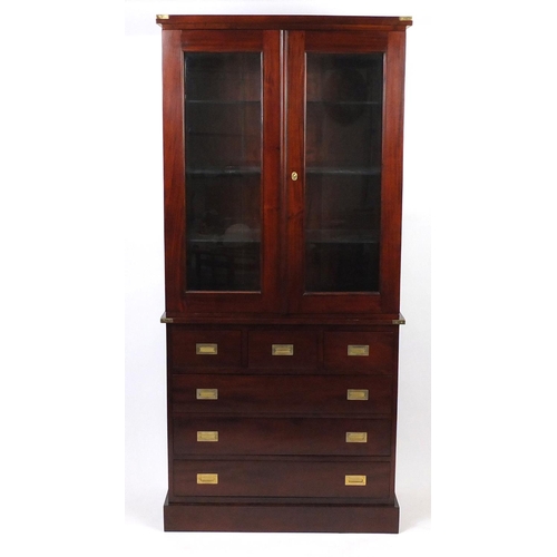 2014 - Mahogany campaign style wall unit fitted, with a pair of glazed doors enclosing glass shelves above ... 