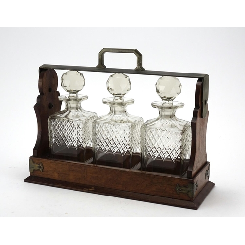 2034 - Oak tantalus with silver plated mounts, housing three glass decanters, retailed by Jay's of Oxford S... 