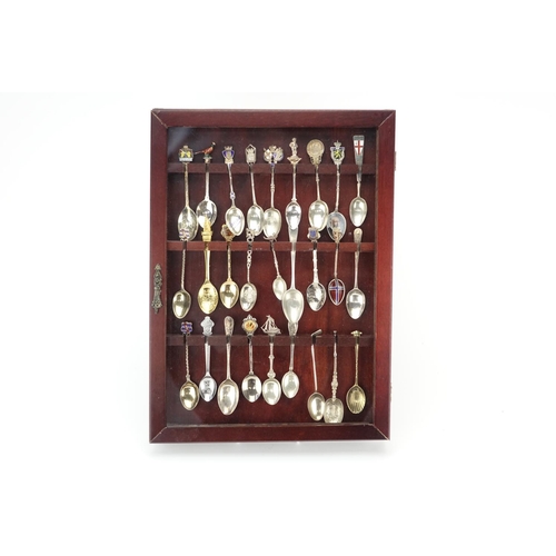 2251 - Silver and white metal souvenir teaspoons, some with enamelled decoration, housed in a mahogany disp... 