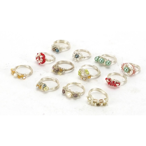 248 - Twelve white metal wire rings set with simulated pearls, freshwater pearls and colourful stones