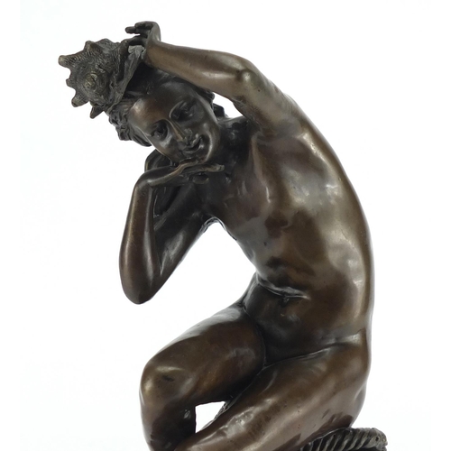 2033 - Patinated bronze figurine of a nude female holding a shell, raised on a circular black marble base, ... 